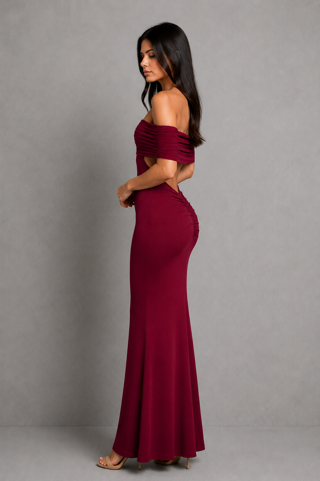 Woman wearing an elegant off-shoulder pleated maxi dress featuring a fitted bodice and flowing floor-length skirt, ideal for weddings, formal events, and evening occasions.