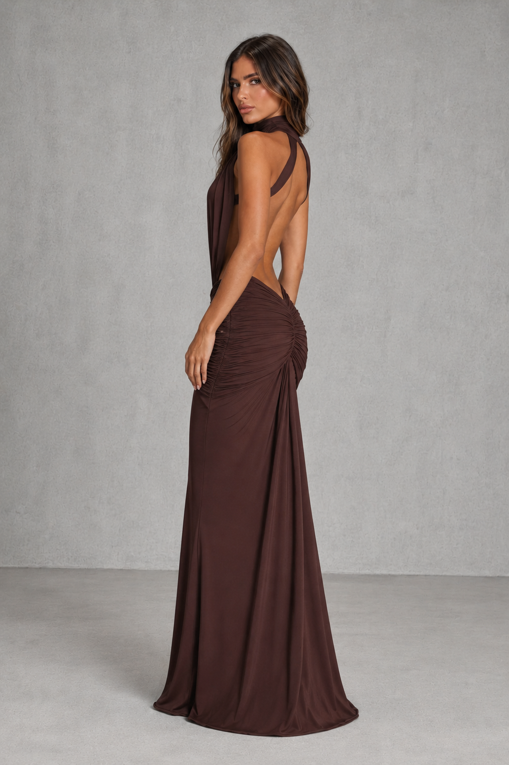 Women's open back mermaid maxi dress in smooth stretch fabric featuring a high neckline, fitted ruched silhouette, dramatic open back, and flowing mermaid skirt for evening and formal occasions.