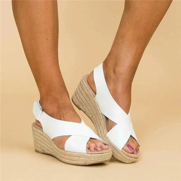 White wedge sandals with jute sole worn by a person on a beige background