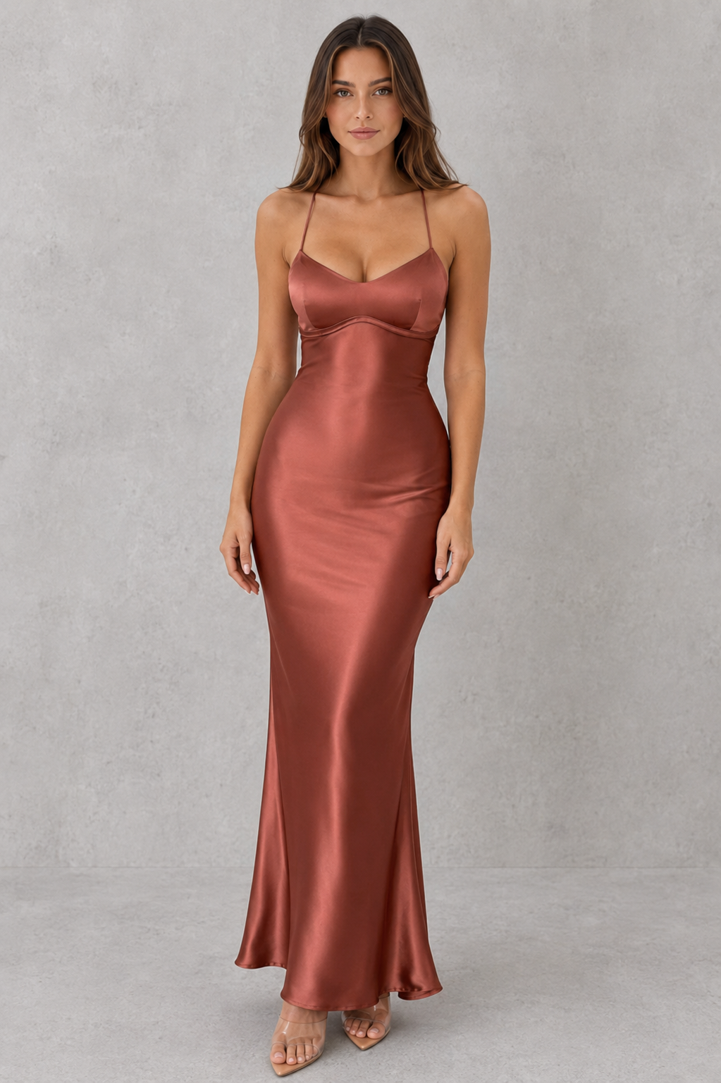 Woman wearing a satin maxi dress with a body-skimming silhouette, delicate shoulder straps, crossover open-back detail, and a floor-length design, styled for formal evening occasions.