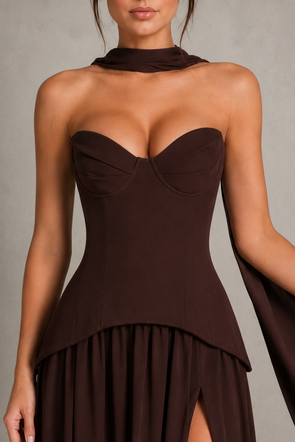 Woman wearing a strapless chiffon maxi dress with a structured corset-inspired bodice, pleated cups, flowing gathered skirt, thigh-high split, and matching chiffon scarf, styled for evening events and formal occasions.