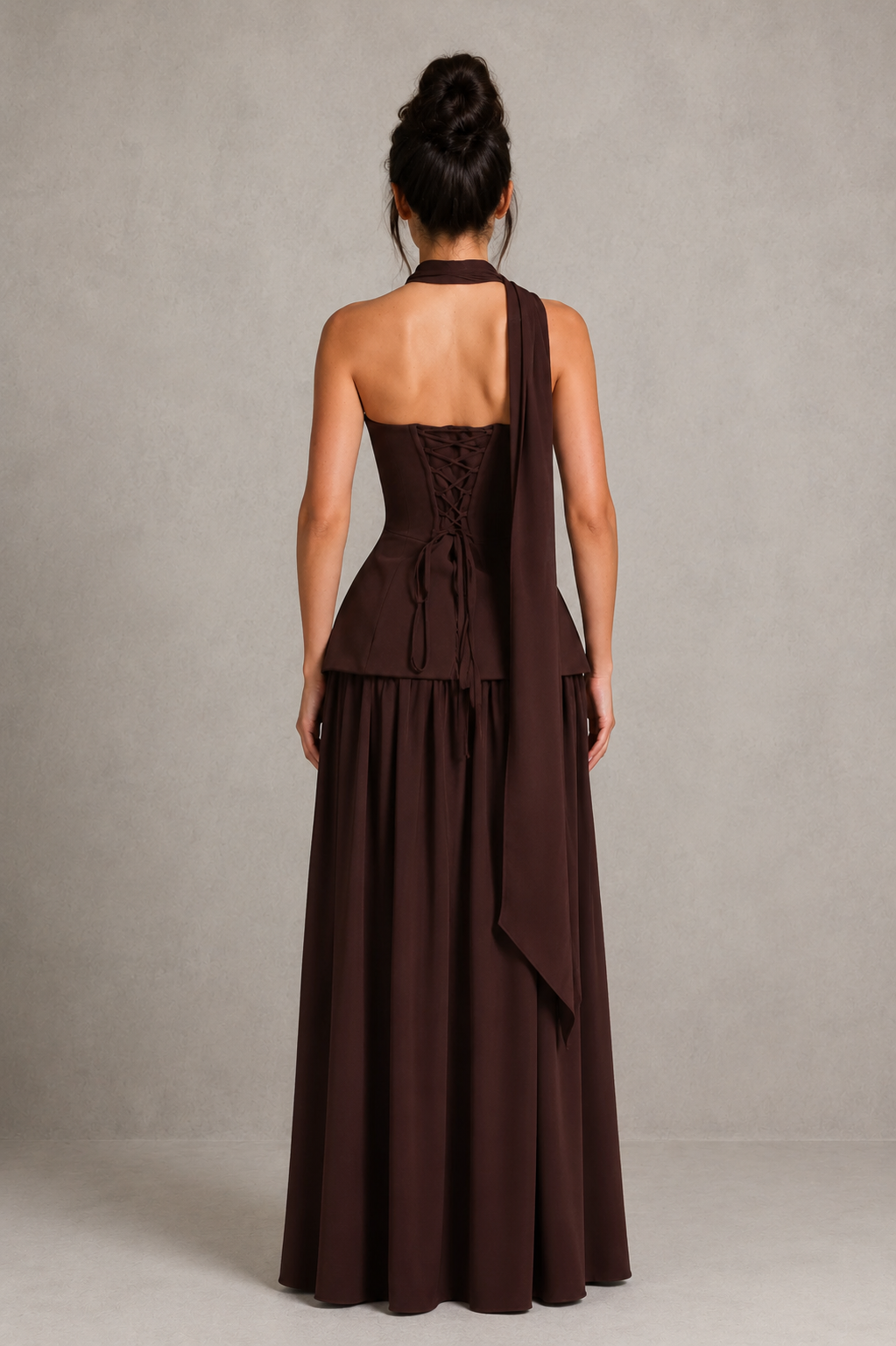 Woman wearing a strapless chiffon maxi dress with a structured corset-inspired bodice, pleated cups, flowing gathered skirt, thigh-high split, and matching chiffon scarf, styled for evening events and formal occasions.