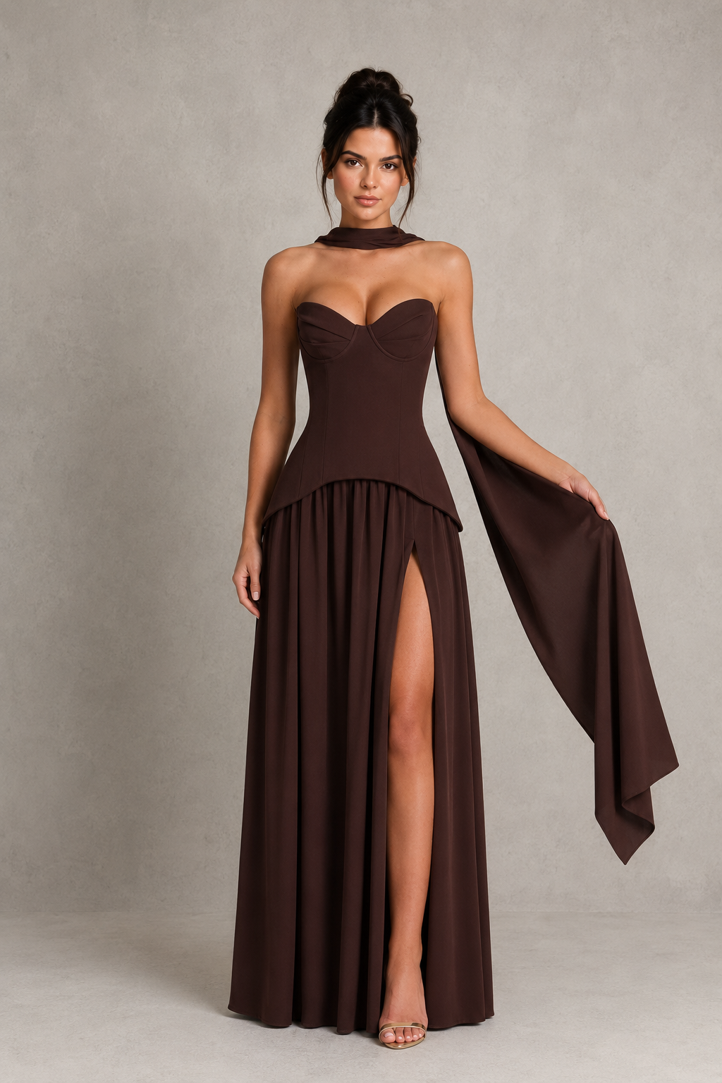 Woman wearing a strapless chiffon maxi dress with a structured corset-inspired bodice, pleated cups, flowing gathered skirt, thigh-high split, and matching chiffon scarf, styled for evening events and formal occasions.