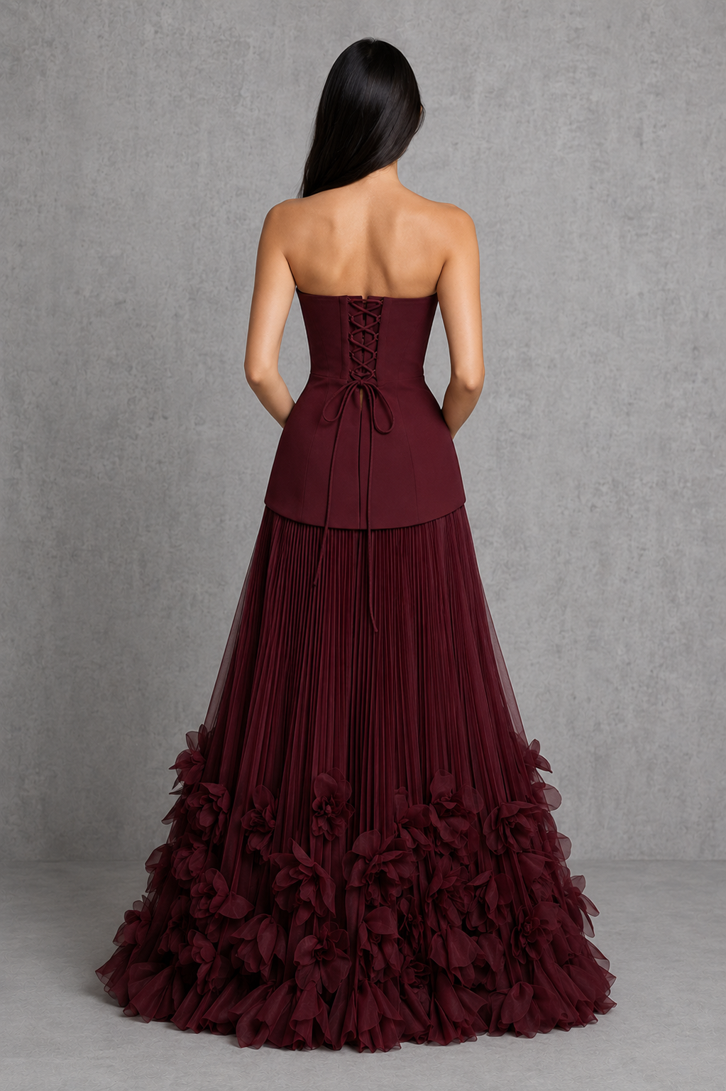 Women’s strapless corset gown with lace-up back, fitted bodice, full pleated skirt, and handcrafted floral appliqué detailing along the hem.