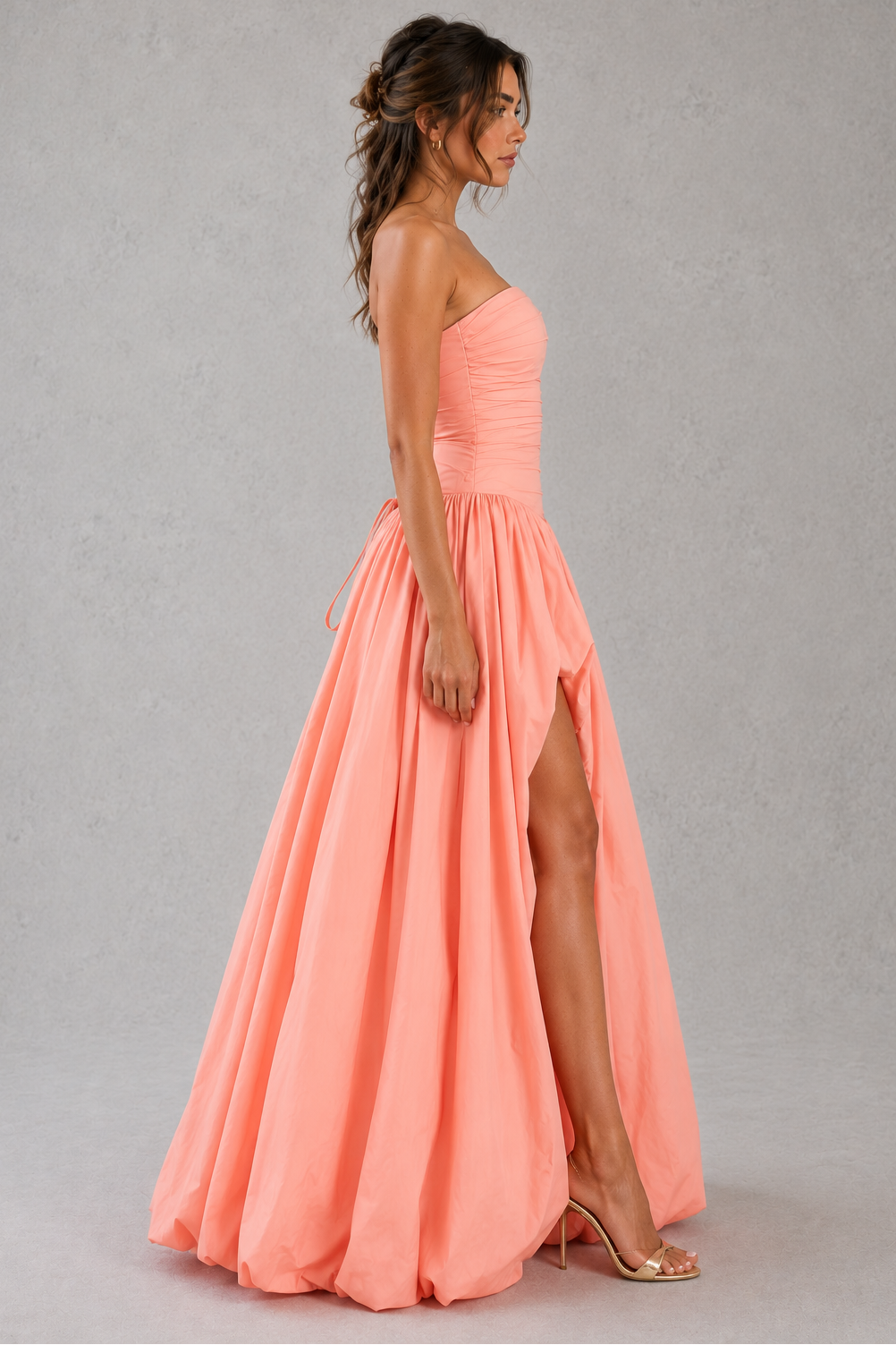 Women's strapless maxi dress with a ruched fitted bodice, dropped waist, lace-up back, dramatic puffball skirt, and thigh-high split, designed for elegant evening events and formal occasions.