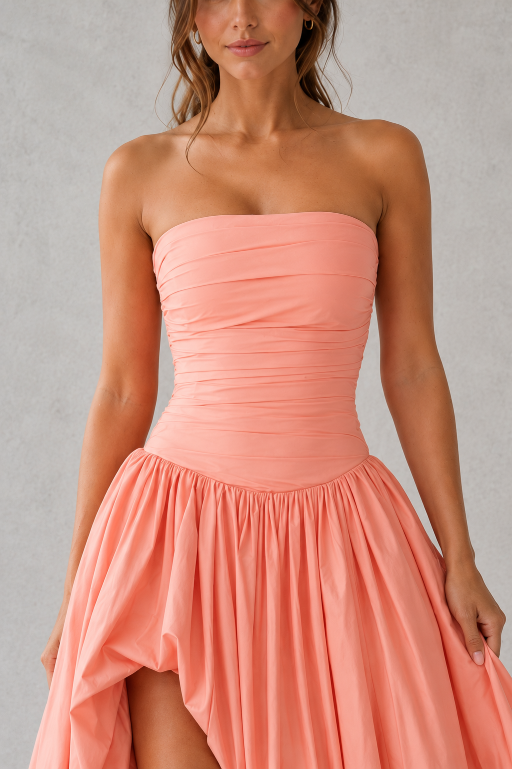 Women's strapless maxi dress with a ruched fitted bodice, dropped waist, lace-up back, dramatic puffball skirt, and thigh-high split, designed for elegant evening events and formal occasions.