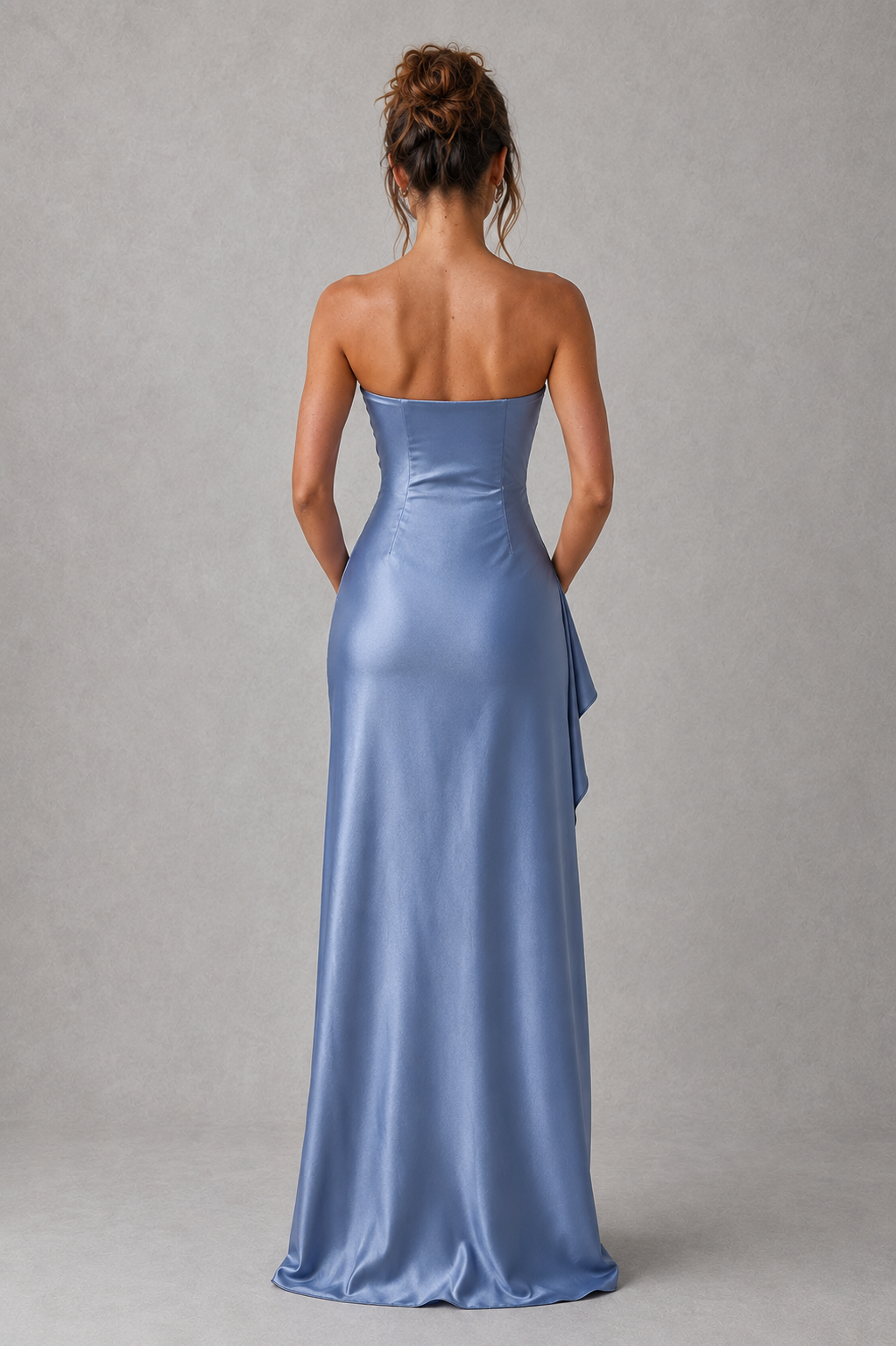 Woman wearing a strapless satin maxi dress with a fitted bodice, asymmetric waist pleating, and a draped thigh-high split skirt. The elegant stretch satin fabric creates a flattering silhouette with graceful movement, ideal for evening events, formal occasions, and special celebrations.