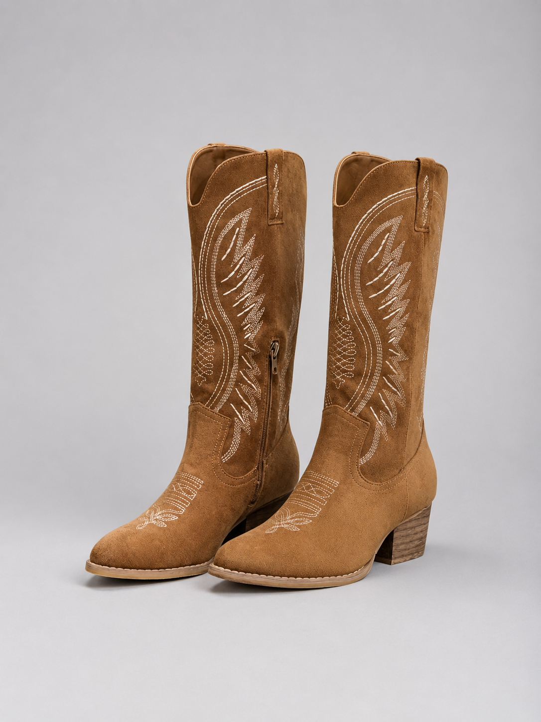 Women’s knee-high suede cowboy boots with western stitching, pointed toe, mid block heel, and classic pull-on design.